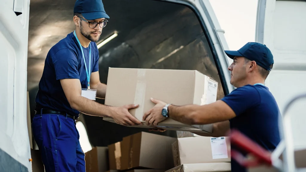delivery men loading carboard boxes van while getting ready shipment